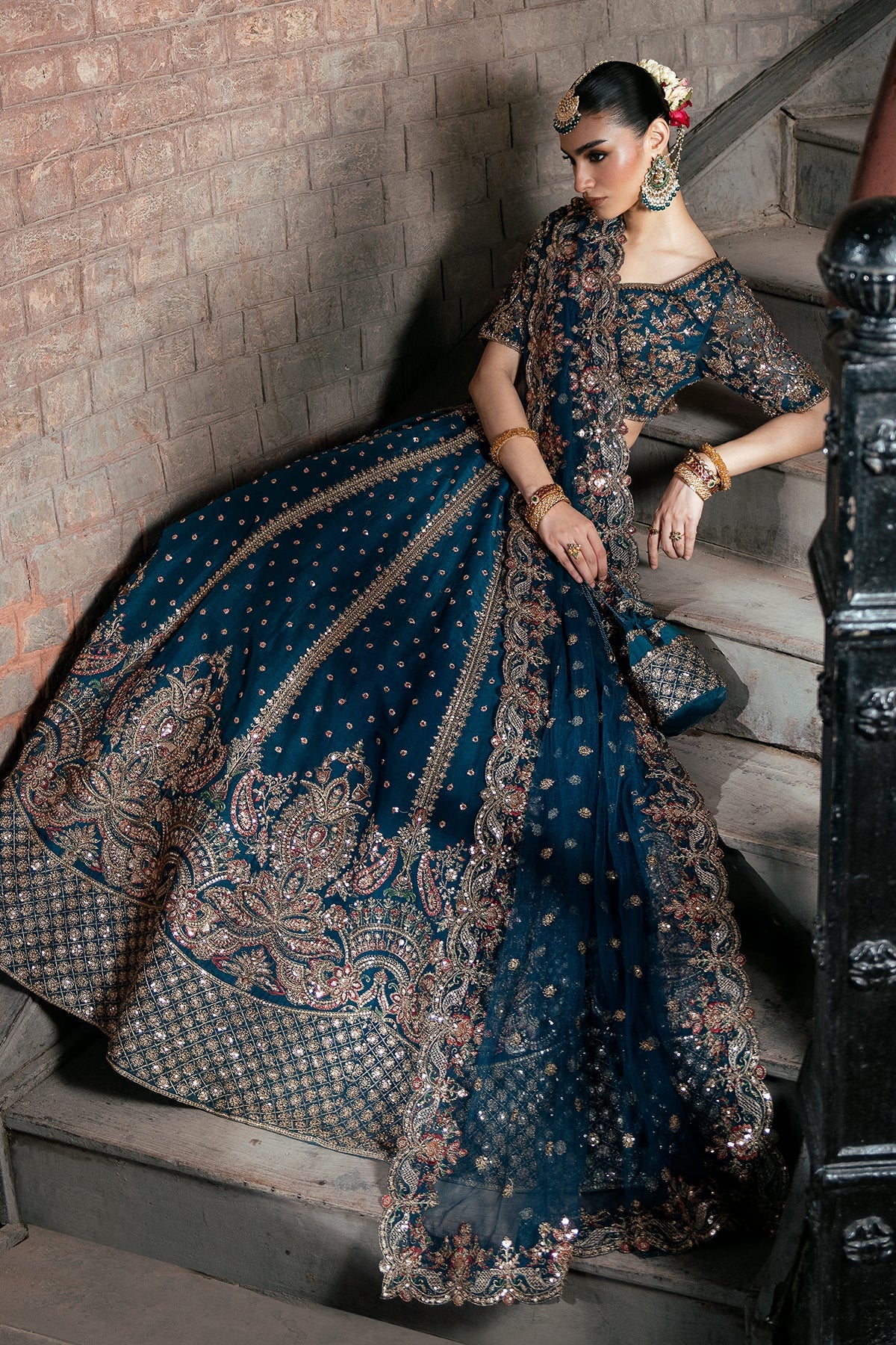 Tabassum, made by MAIRAZ — deep teal lehenga choli, seated view showing skirt border